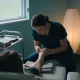 A practitioner examining a patient's foot at a treatment chair in an Australian clinic, with a trolley of plain towels and a tray beside them.