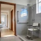 An accessible Australian bathroom with a level-entry shower, a fold-down seat, a grab rail and a wide flat-threshold doorway.
